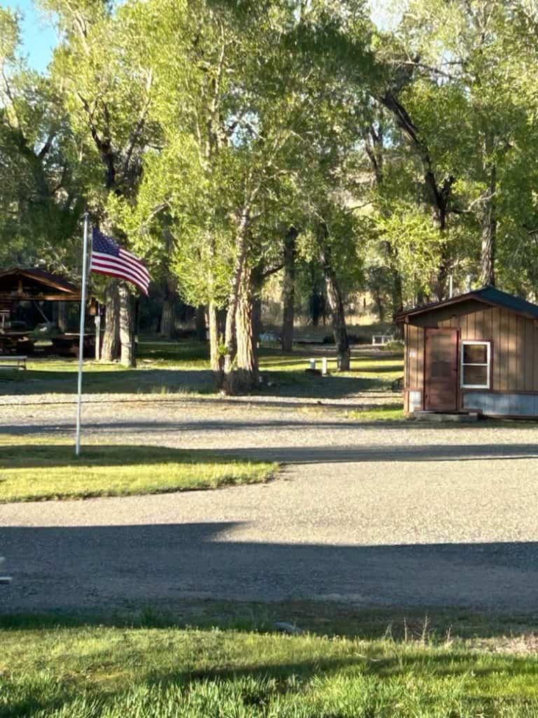 American flag flying near trees and small building at Oasis Motel & RV Park.