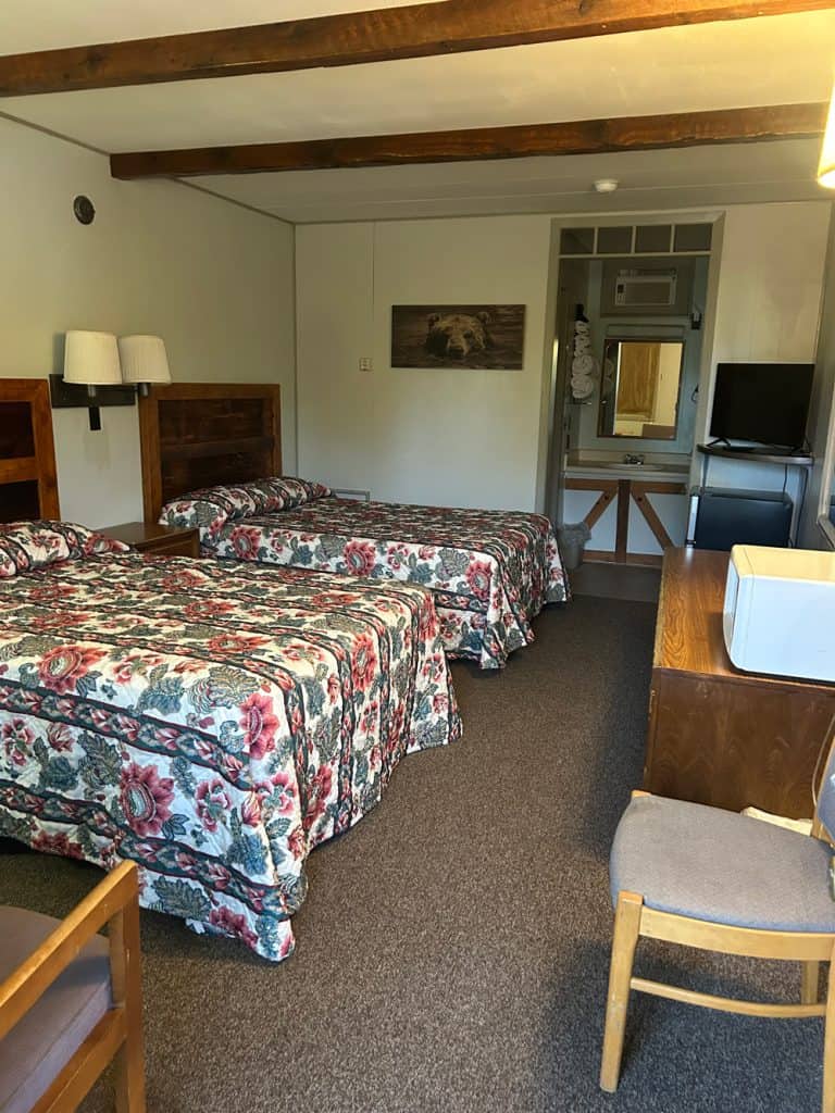 Interior view of motel room with two beds, TV, and wooden furniture in Meeteetse, Wyoming.