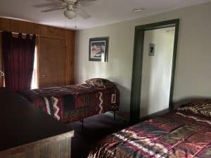 Interior view of a motel room with two beds, wooden closet, and ceiling fan.