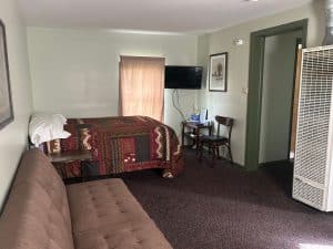 Comfortable motel room with bed, sofa, and TV at Oasis Motel & RV Park.