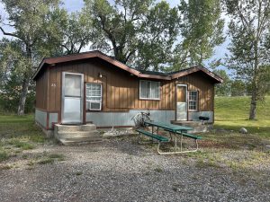 Cozy cabin at Oasis Motel & RV Park in Meeteetse, Wyoming with picnic table outside.