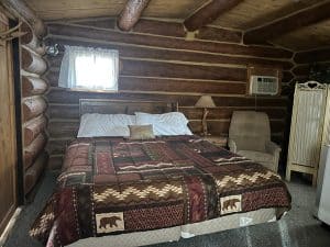 Interior view of a log cabin bedroom with a large bed and rustic decor.