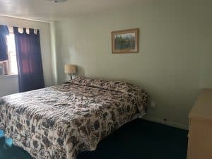 Interior of a motel room with a large bed, window, and artwork.